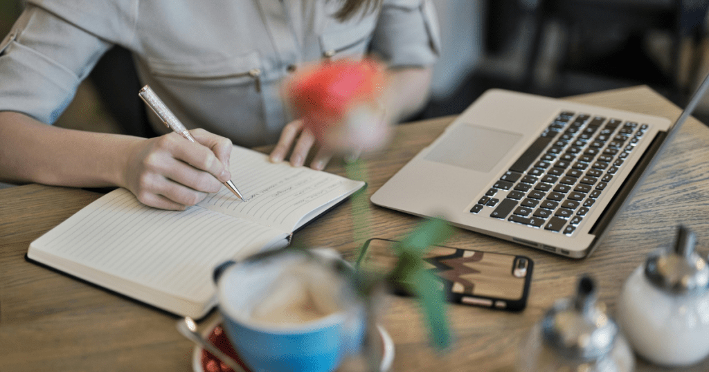 hand writing on a notebook, table with laptop